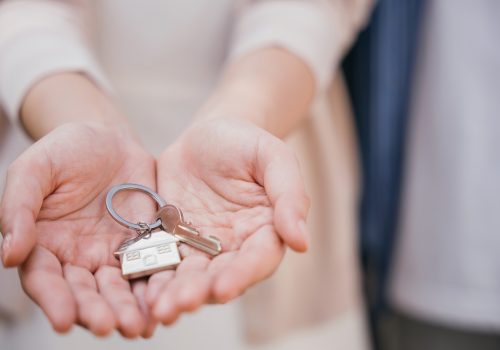 Female landlord gives keys symbolizing new home purchase. Represents successful property deal tenant